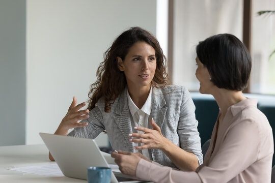 To kolleger taler sammen ved et skrivebord med en bærbar computer